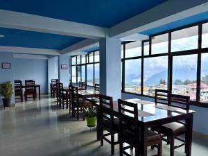 a dining room with tables and chairs and windows at Hotel Vivid Tawang in Tawang