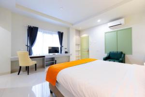 1 dormitorio con 1 cama, escritorio y sillas en Sans Hotel 88 Andalan Surabaya by RedDoorz, en Surabaya