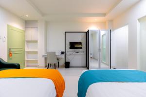 a white room with two beds and a desk at Sans Hotel 88 Andalan Surabaya by RedDoorz in Surabaya