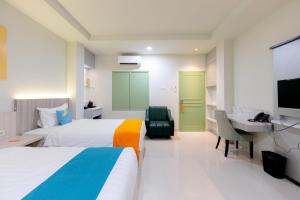 Habitación de hotel con 2 camas, escritorio y TV. en Sans Hotel 88 Andalan Surabaya by RedDoorz, en Surabaya