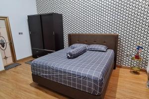 1 dormitorio con 1 cama con 2 almohadas y armario en Shazia House - Modern and Cozy Home with 3 Bedrooms and Private Pool en Tanjungkarang