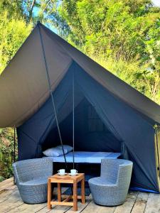 uma tenda com duas cadeiras e uma mesa em Ella Nine Arch Glamp Site em Ella