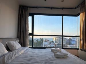 a bed in a room with a large window at The Base Central Pattaya by Leya in Pattaya Central +36 photos