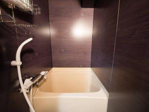 a bathroom with a bath tub with a light on the wall at TasoneUrbanStayOsaka なんば日本橋南不夜城704 in Osaka