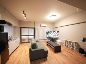 a living room with a couch and a flat screen tv at TasoneUrbanStayOsaka なんば日本橋南不夜城704 in Osaka