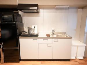 a kitchen with a sink and a black refrigerator at TasoneUrbanStayOsaka なんば日本橋南不夜城704 in Osaka