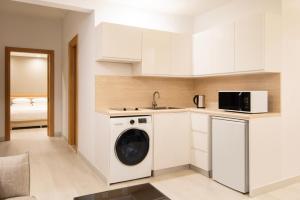 uma cozinha com uma máquina de lavar roupa e um lavatório em Marriott Executive Apartments City Center Doha em Doha