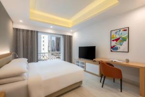 Marriott Executive Apartments City Center Doha في الدوحة: غرفة فندقية فيها سرير ومكتب وتلفزيون