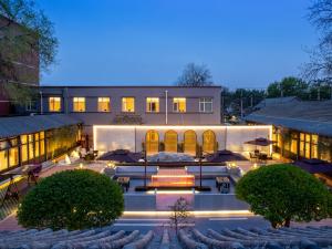 an exterior view of a building with tables and umbrellas at Yunju Hotel Beijing Yonghe Palace Guijie Siheyuan in Beijing