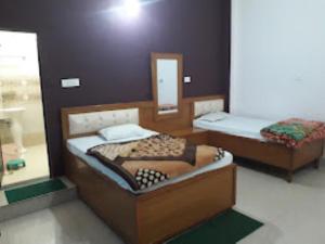 Habitación con 2 camas y espejo. en HOTEL KALASH GUEST HOUSE AND RESTAURANT Kushinagar en Kushinagar