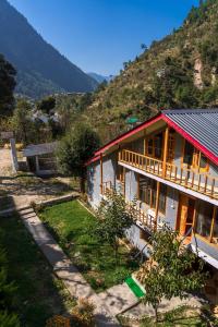 a house with a mountain in the background at Boho Grove Cafe & Stay, Tirthan Valley in Banjār