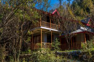 a house with a balcony in the woods at Boho Grove Cafe & Stay, Tirthan Valley in Banjār
