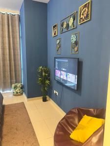 Luxurious 2 Bedroom 5 Mins from Burj Khalifa في دبي: غرفة معيشة مع تلفزيون على جدار أزرق