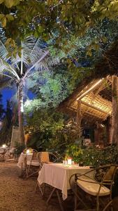un restaurant avec des tables, des chaises et un palmier dans l'établissement Atii Garden Bungalows, à Nungwi