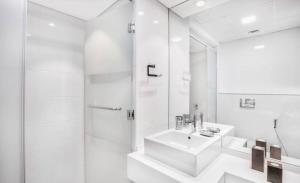 Luxurious 2 Bedroom 5 Mins from Burj Khalifa في دبي: حمام أبيض مع حوض ودش