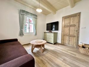 a living room with a couch and a table and a television at Cottage Janovice in Rudník