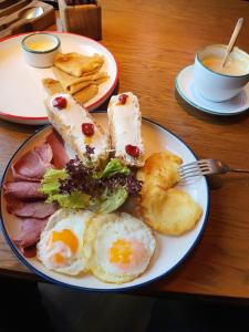 a plate of breakfast food with eggs and ham on a table at Terrabella in Bishkek