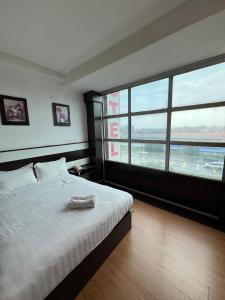 a bedroom with a white bed with a large window at Hotel Economy Kapar in Kapar