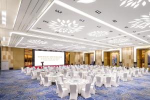 un gran salón de banquetes con mesas blancas y sillas blancas en Grand Mercure Jinan Sunshine, en Jinan