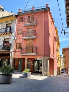 un edificio rojo con balcones en una calle de la ciudad en l'Apartament de la Plaça, en Puigcerdà