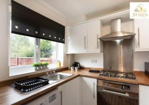 cocina con fregadero y fogones horno superior en 3 Bedroom Apartment, family & business - Big special offer for long stays en Lincolnshire