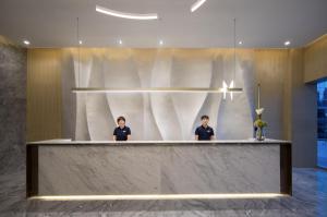 two people standing behind a counter in a lobby at Citadines Keqiao Shaoxing in Shaoxing