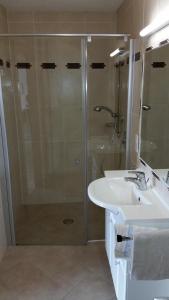 La salle de bains est pourvue d'une douche en verre et d'un lavabo. dans l'établissement Haus am Waldrand, à Thiersee