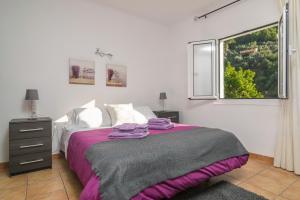 een slaapkamer met een bed met paarse lakens en een raam bij Cas Decu in Fornalutx