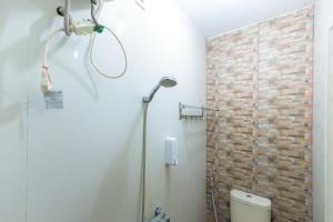 een douche in een badkamer met een bakstenen muur bij RedDoorz at Osuko Residence Sukomanunggal Jaya in Surabaya