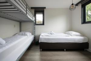 two twin beds in a room with two windows at 20, Nestled in the woods, Big Chalet and Garden! in Oisterwijk