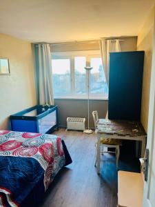 een slaapkamer met een bed, een bureau en een raam bij Booking in Clichy