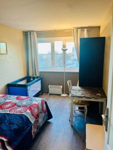 a bedroom with a bed and a desk and a window at Booking in Clichy