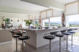 una cocina con taburetes en un bar con vistas en Lookout Lodge en Plettenberg Bay