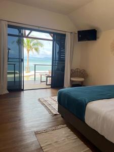 a bedroom with a bed and a view of the ocean at Le Shelby Samui Beach Resort Cottage in Koh Samui