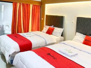 - deux lits dans une chambre d'hôtel rouge et blanche dans l'établissement RedDoorz near Museum Gunung Merapi, à Yogyakarta