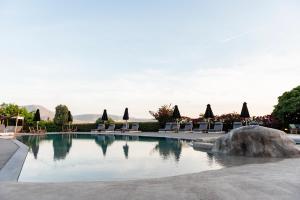 a pool at a resort with chairs and a rock at Paros Agnanti Resort & Spa in Parikia