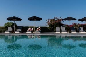 a group of people sitting under umbrellas next to a swimming pool at Paros Agnanti Resort & Spa in Parikia
