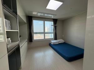 a small room with a blue bed and a window at Sea View Doubleroom in Incheon