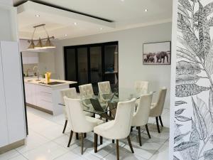 a dining room and kitchen with a glass table and white chairs at Essence Lifestyle Self-Catering Accommodation - Academia in Windhoek