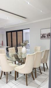 a dining room with a glass table and white chairs at Essence Lifestyle Self-Catering Accommodation - Academia in Windhoek