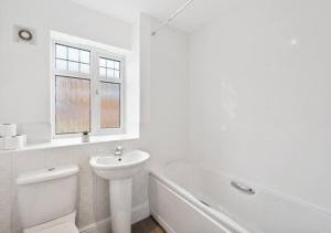 a white bathroom with a sink and a toilet and a tub at 4 Bedroom Apartment, near the airport & Free WiFi-Parking in Lincolnshire