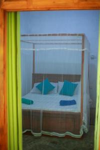 una camera da letto con letto a baldacchino e cuscini blu e verdi di Yino Villa a Midigama East