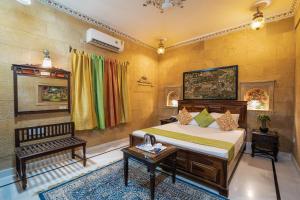 ein Schlafzimmer mit einem Bett und einer Bank in einem Zimmer in der Unterkunft Hotel The Golden House in Jaisalmer