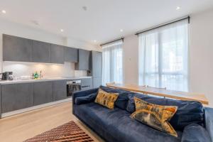 a living room with a blue couch and a kitchen at Charming & Stylish 1BD Flat - Bethnal Green in London