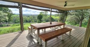 a wooden table and bench on a deck with a view at Hinterland Hideaway Farm Stay in Wolvi