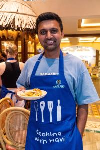 a man wearing a blue apron holding a plate of food at Seahorse Signature Danang Hotel by Haviland in Danang
