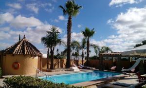 a swimming pool with palm trees and a building at Alojamiento el Chaparro Barbate junto a la venta el loro in Barbate