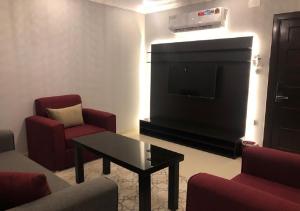 salon z telewizorem z płaskim ekranem i czerwonymi krzesłami w obiekcie DORRA ABHUR w mieście Obhor