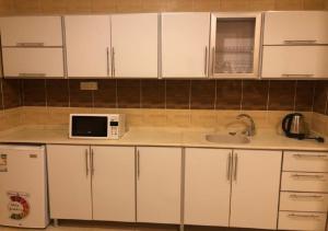 a kitchen with white cabinets and a microwave at DORRA ABHUR in Obhor