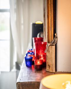 a wooden table with red and blue glasses on it at Haven 1 in Sint Anna ter Muiden